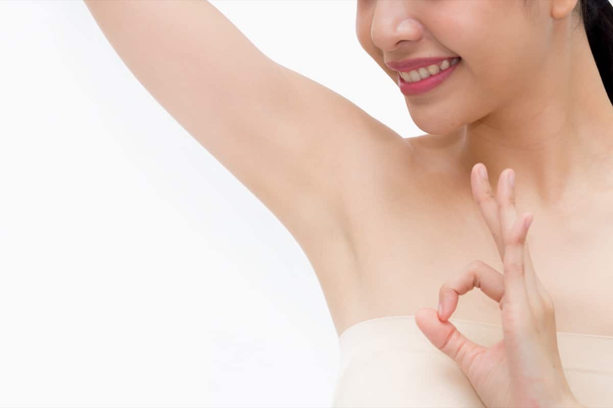 Young Asian woman lifting hands up to show off clean and hygienic armpits or underarms and giving okay sign - smooth armpit cleanliness and protection concept