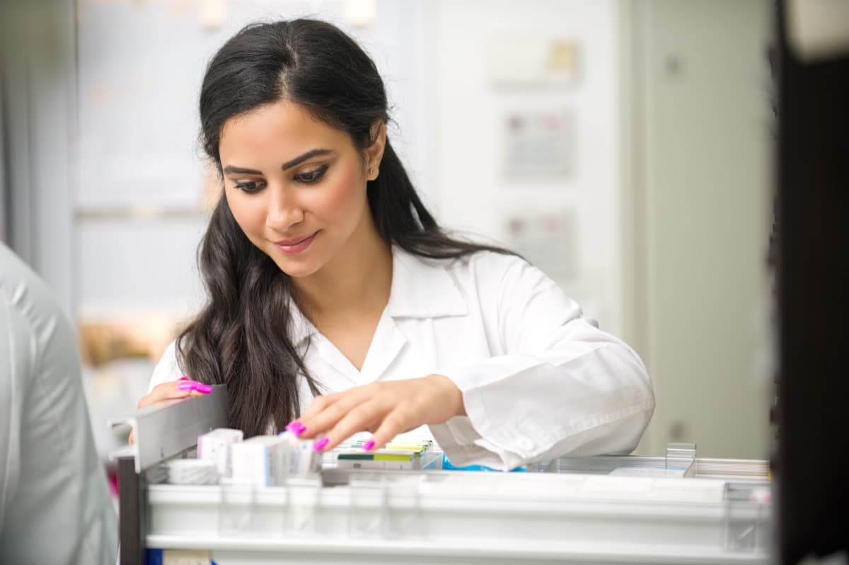 Beautiful female model pharmacist looking at medicine